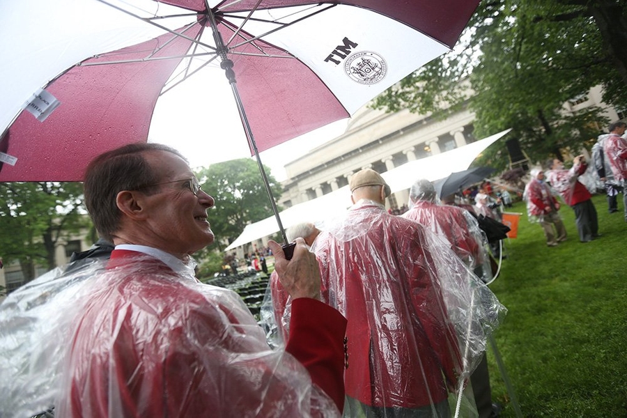 Alumni from MIT's Class of 1963 — celebrating their 50th anniversary and their new red coats — enter the rainy Killian Court.