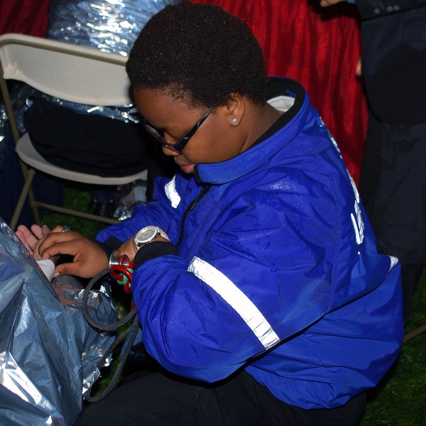 EMT Anita Wamakima, ’15, monitors the vital signs of a badly chilled patient in the medical tent at MIT’s 2013 Commencement.