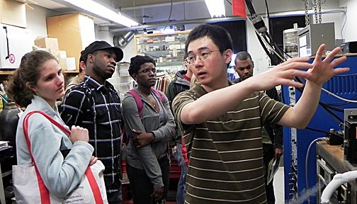 Summer Scholars listen to a presentation by Peng Wei, a post-doctoral associate working on topological insulators in the Moodera Research Group at MIT. From left: Sarah Goodman, James Haynes and Mila’na Jones. Standing behind Wei are David Mackanic (obscured) and Alvin Mercedes.