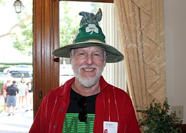 A person wears a green pointy hat and red button-up shirt