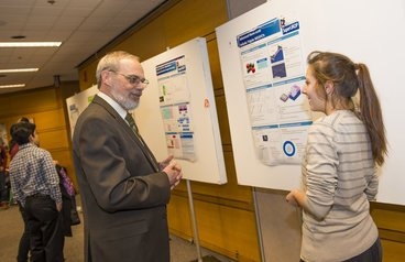 Eric Grimson, MIT chancellor for academic advancement, talks with Rose Abramson, '15, about her work with Jesus del Alamo, director of the Microsystems Technology Laboratories, on developing transistors made with silicon alternatives and sized below 10 nanometers.