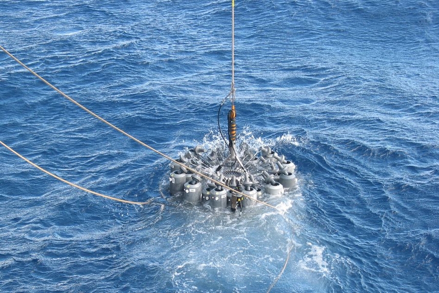 Scientists on an oceanographic research ship lower a rosette of 24 bottles into the ocean to capture samples of wild microbes in their natural habitat.