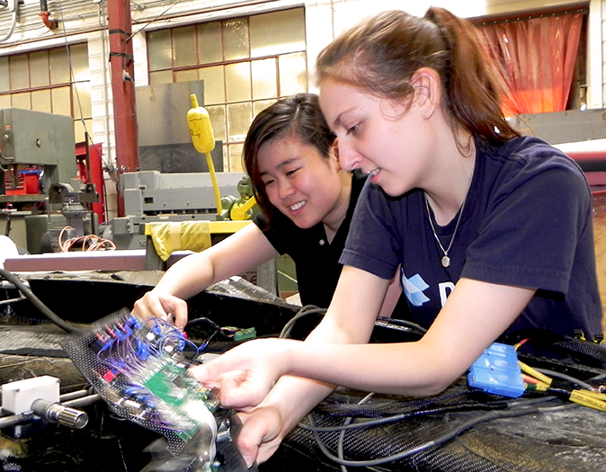 Chao (left) and Abramson remove the steering electronics panel in the solar car.