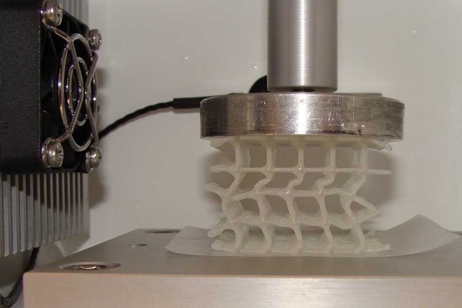 A 3D-printed soft, flexible scaffold that is coated in wax and is being compressed in a temperature-controlled chamber. Heating a composite whose wax coating has broken can enable the wax to soften and "heal" to restore its original strength and properties.