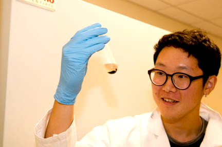 John Lee holds a vial of lead sulfide (PbS) quantum dots, which are dissolved in water, where they are attached to bacteriophages. Lee studied the use of virus-based quantum dot nanowires for solar cell applications.