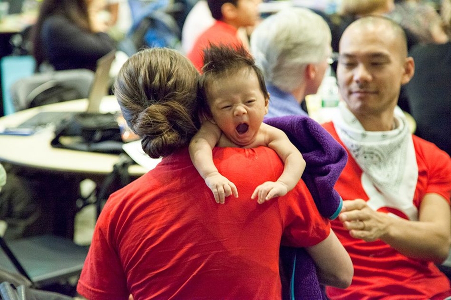 Baby Pau Wang-Levy with his mom Taylor Levy and dad Che-Wei Wang (background, red shirt), two organizers of the hackathon and students at the MIT Media Lab in the Playful Systems Group.