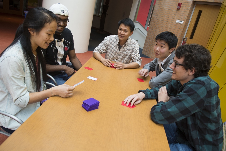 6.UAT undergraduate TA Jenny Shen '15 describes a word she has drawn from a deck of cards that was the product of an effort involving a number of TAs, students, and 6.UAT creator and EECS senior lecturer Tony Eng (center). Anthony Adams '15, second from left, assists his teammate while Benoit Landry (far right), an EECS grad student, and Francis Chen '15 attempt to identify the mystery taboo card ...
