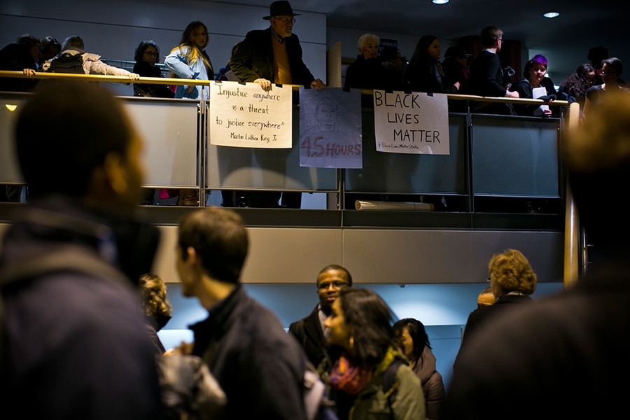 A crowded room with two levels, as second level attendants hold posters in support of Black Lives Matter movement.