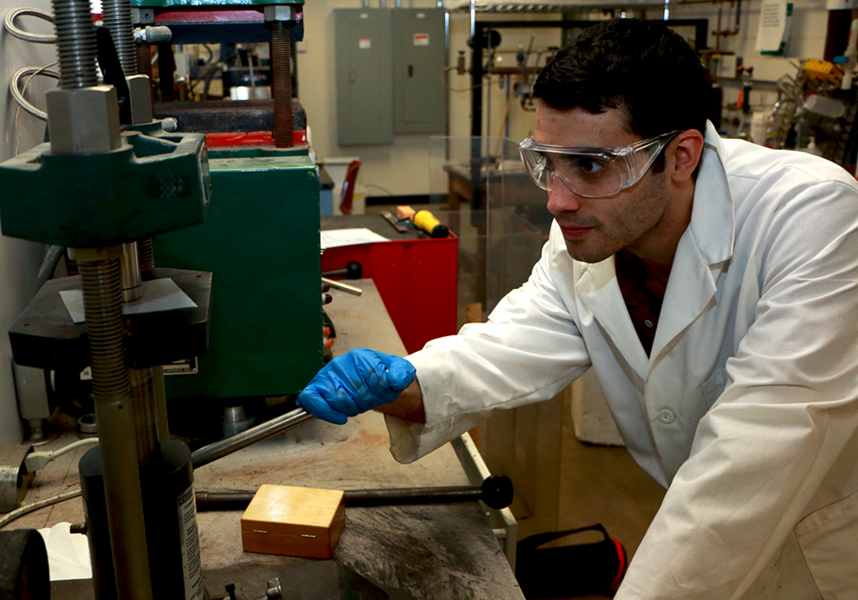 MIT graduate student Zack Cordero demonstrates a uniaxial press used for consolidating loose powder into a pellet. Working under Materials Science and Engineering Department chair Christopher A. Schuh, Cordero has developed extremely hard, finely grained tungsten alloy powders and compacts.