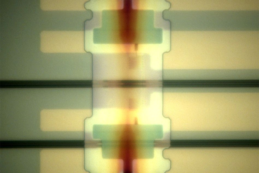 One of the researchers' new photon detectors, deposited athwart a light channel — or "waveguide" (horizontal black band) — on a silicon optical chip.