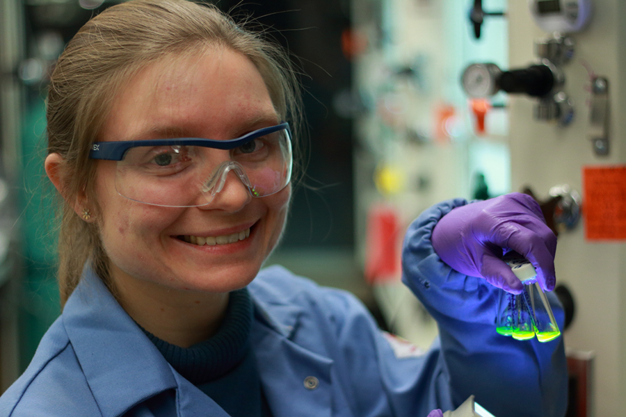 MIT chemistry graduate student Jolene Mork holds bottles of fluorescent quantum dots. Mork examines how fast energy transfers from one quantum dot to another.
