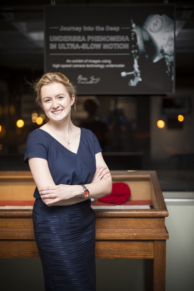 Grace Young ’14 stands in her ultra-slow-motion underwater-photography exhibit at the Wiesner Student Art Gallery. Young is now developing new tools for deep-sea research as a PhD student at the University of Oxford.