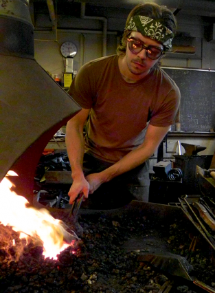 James Hunter heats a metal blade in hot coals to shape it in the MIT Glass Lab and Forge.