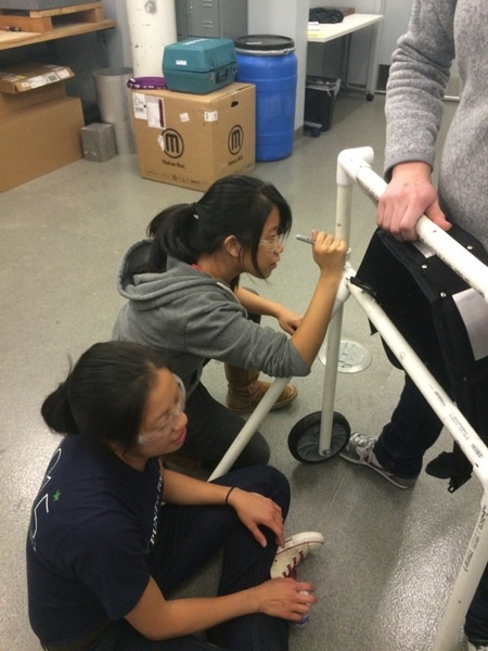 A team prototyping a hands-free walker fits PVC pieces together.