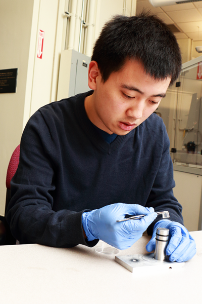 MIT biological engineering graduate student Bo Qing demonstrates how he loads a polydimethylsiloxane gel onto a post used in a nanoindenter to measure the gel's impact response. The instrument in the NanoMechanical Technology Lab at MIT pushes an indenter into the gel material, which is designed to mimic brain tissue, at very high loading rates. The work is part of a study under Associate Professo...