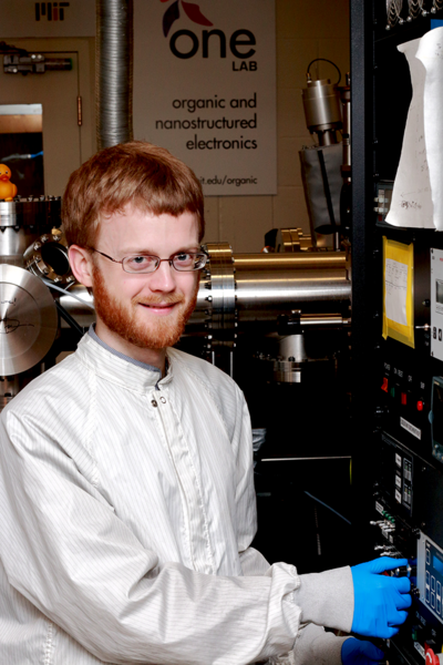 MIT physics graduate student Patrick Brown stands at the controls for a magnetron sputterer deposition chamber, used in the fabrication of charge-transport layers for quantum-dot solar cells.