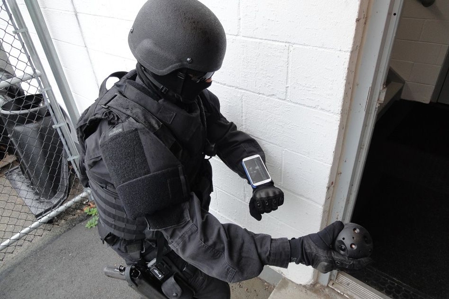 A police officer prepares to throw the Explorer into an unseen stairwell. The camera will then immediately send images of the area back to the smartphone on the officer's wrist.