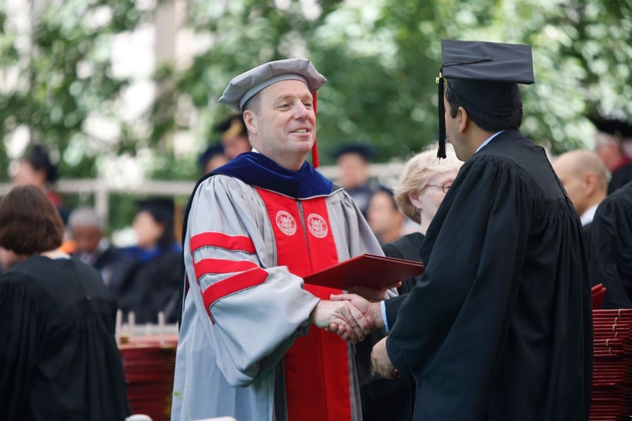 Provost Martin Schmidt hands a diploma to a new graduate.