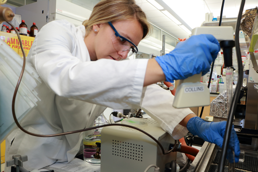 Summer Scholar Lisa Savagian makes adjustments to a machine for robotically depositing charged polymers, layer by layer, onto a glass substrate for a drug delivery mechanism under study. Her project in the lab of Professor Paula Hammond focused on creating a layered polymer infused with gold nanorods that can hold a drug until its release is triggered by exposure to laser light.