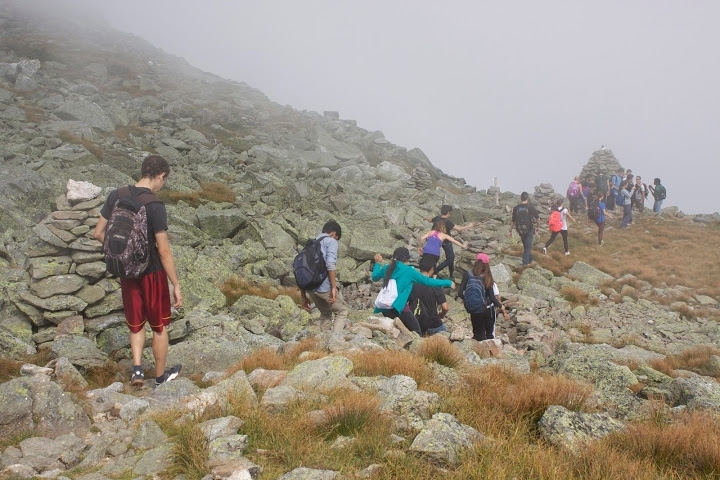 Students walk through a cloud as they navigate Mount Washington’s rocky terrain.