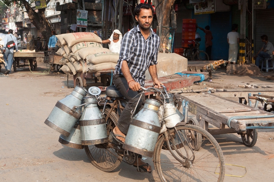 A man delivers pails of fresh milk to customers in rural India.