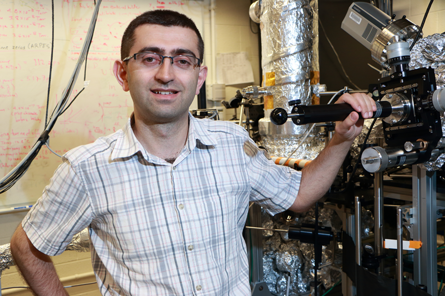 Nuh Gedik stands near a customized experimental chamber for studying the energy and momentum of electrons in complex materials. One example of these materials is topological insulators, which do not conduct electricity in their bulk but have an exotic conducting state on their surface.