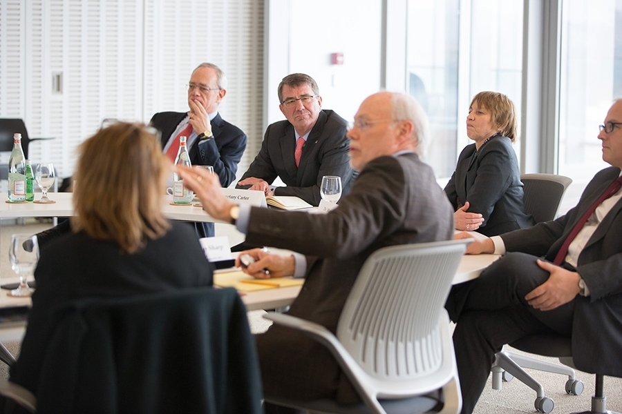 Photo of half a dozen people sitting around a table in a white conference room