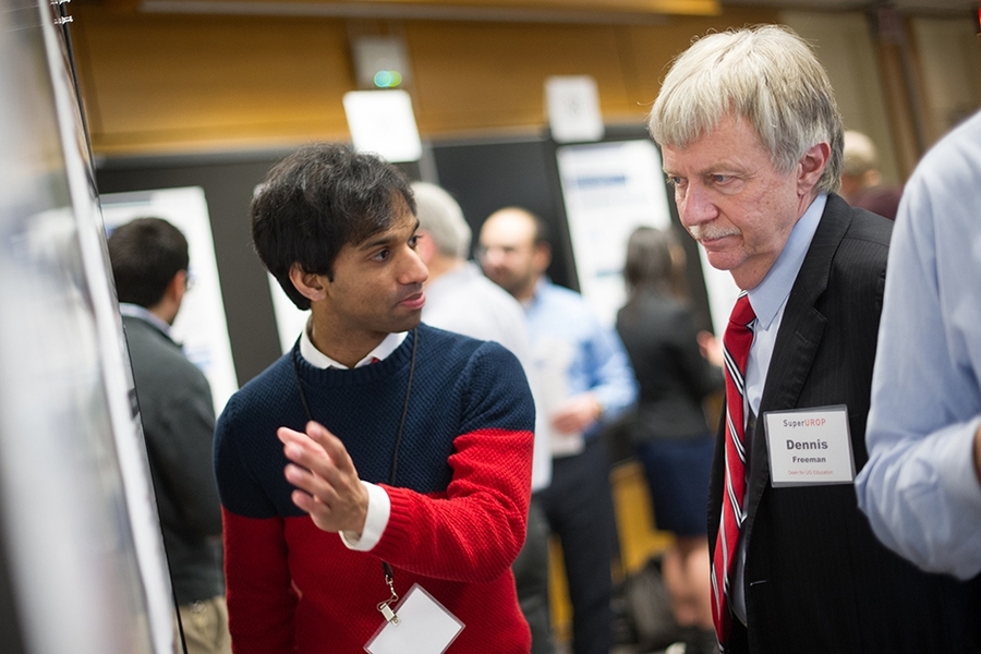 Senior Pranam Chatterjee (left) explains his SuperUROP project to Dennis Freeman, dean for undergraduate education.