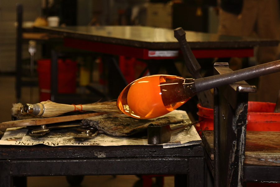 Arresting workpiece: An eggplant-shaped multi-colored glass at an early stage will be heated, expanded, and worked into final shape.