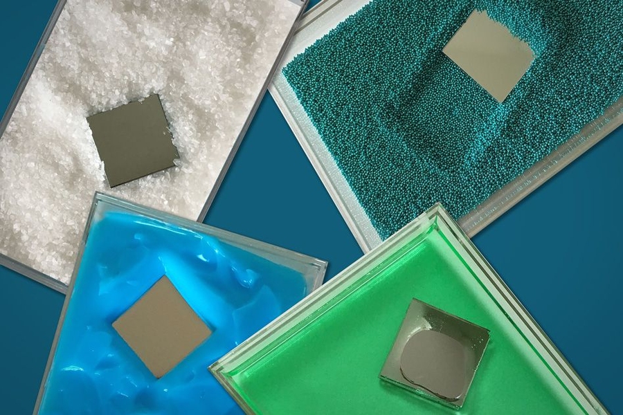 The photograph shows a square-shaped “intruder” plunging through various material, including coarse, salt-like grains (white) and fine sand (blueish green), as well as more viscous (green) and pasty (blue) materials.