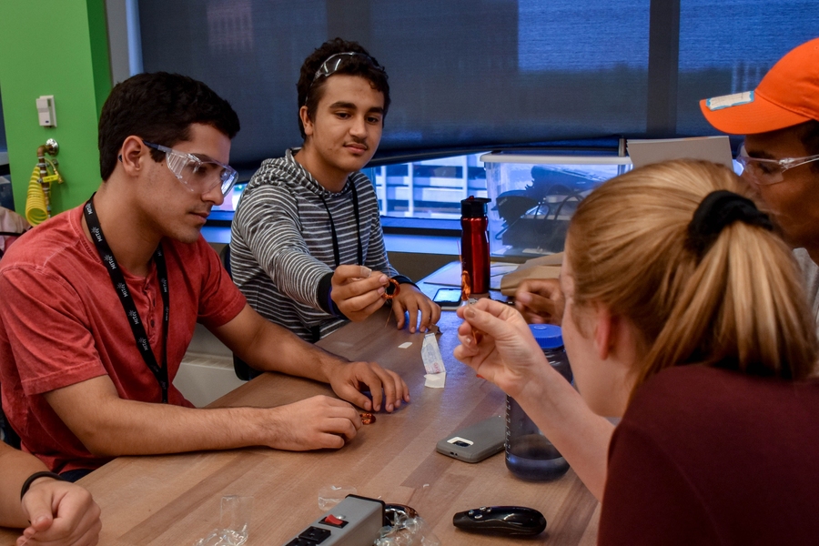 While participating in Steven Leeb’s direct-current motor lab activity, freshmen Dylan Lewis (left) and Jose Domingo Soto Rivera compare rotors made using magnet wire with counselor and sophomore Rebecca Eisenach.