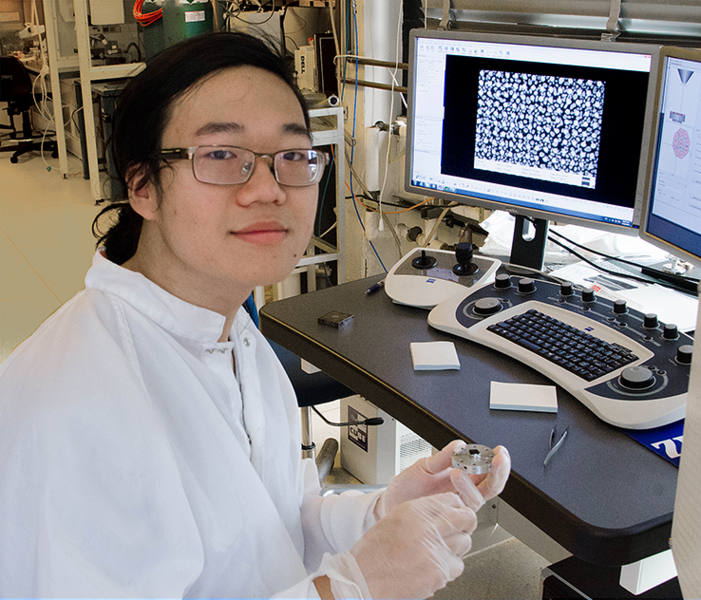 Summer Scholar Justin Cheng holds an experimental sample of nanostructured gold on silicon that has potential for use in sensors and display technologies based on its selective light absorption properties.