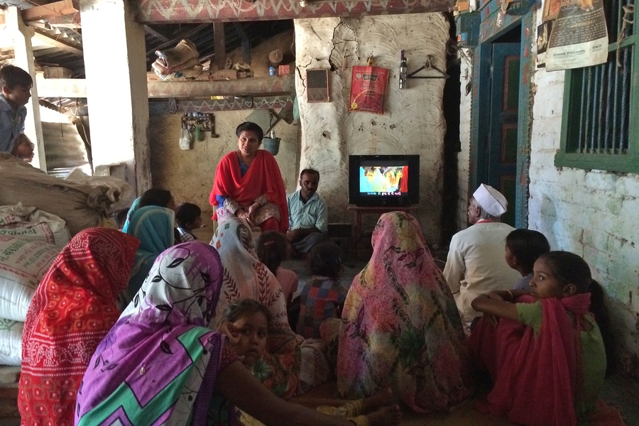 Community members from a rural village outside of Ahmedabad, India, gather to watch videos designed to increase literacy. 