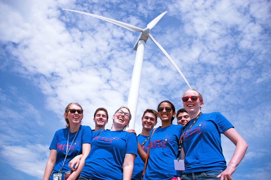 MIT freshmen and counselors pose in front of the Hull Wind turbine next to Hull High School. The turbine has provided renewable energy for the town since 2001.