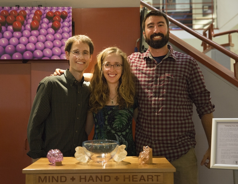 Sculpture designers and Random Hall heads of house Jared (left) and Laurie Berezin stand with woodworker Mark Ferioli (right), beside the sculpture they helped to create.