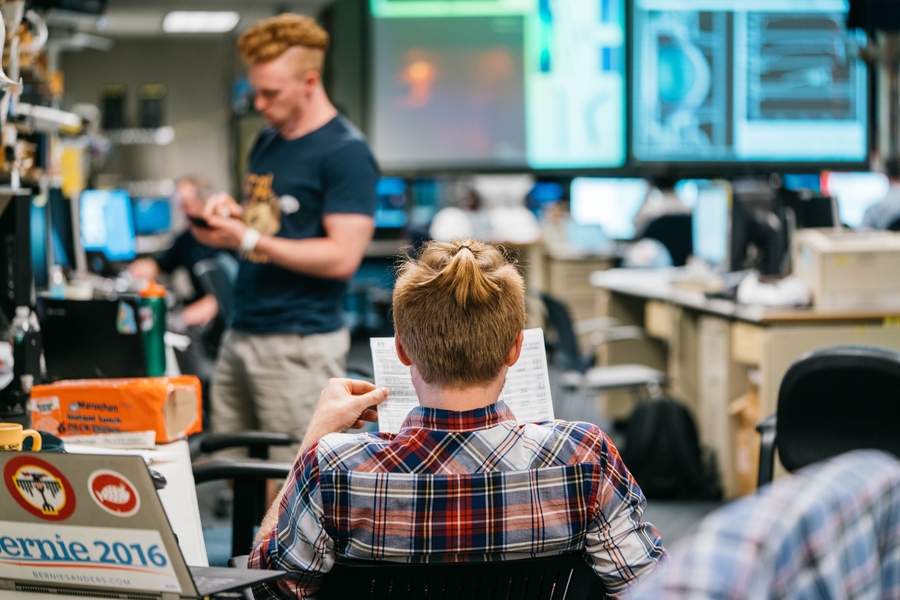 Research scientist Eric Edlund (seated) faces the large display screens that dominate the control room. Edlund completed his PhD working on C-Mod in 2009. Graduate student Alex Tingly, meanwhile, works on his own research.