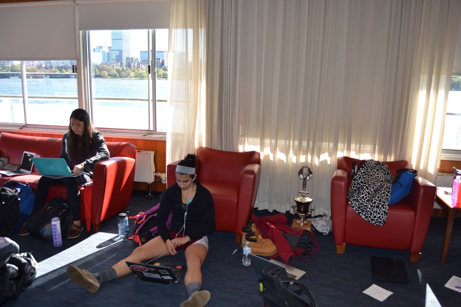 Teammates Michelle Lauer (left) and Sylvia Sarnik sit in the boathouse in the hours before making MIT history. The space has a camped-out family feel. Nervous first-year students lob earnest question at their elders: “What should I eat before the race?” 