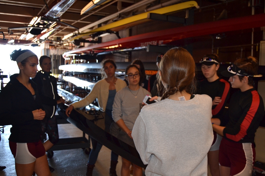 Coxswain Chloe Thacker (center right, with back turned) briefs members of the Varsity 8 about the high wind conditions along the 5-km course. Left to right: Sylvia Sarnik, Claire Martin-Doyle (head coach), Priya Veeraraghavan (captain), Sharon Wu (captain), Kelly Barton, Valerie Hunter, Elizabeth Martin, and Annika Rollok. “Wear layers,” says Thacker. “Be ready for water in the boat.”