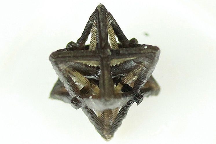 Each beam and truss is made from one of two materials that expand at different rates with heat. As the entire structure warms up, the inner beams, expanding faster, pull the outer beams inward, shrinking the structure overall. 
