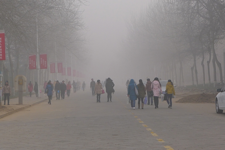 University students walk through dense air pollution at Anyang Normal University in Henan Province, China.