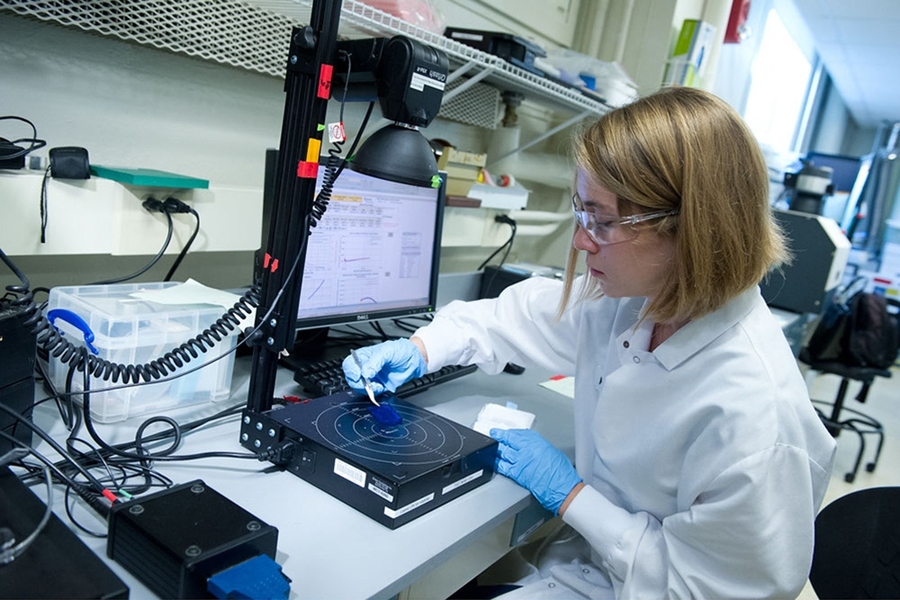 Graduate student Mallory Jensen performs a test to determine the spatially averaged lifetime of excited electrons in a sample silicon wafer. A high-intensity, broadband flash of light excites electrons in the wafer, inducing voltage in a sensor beneath.