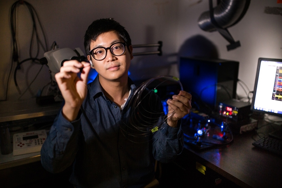 Graduate student Seongjun Park holds an example of a new flexible fiber, which is no bigger than a human hair and has successfully delivered a combination of optical, electrical, and chemical signals back and forth into the brain.