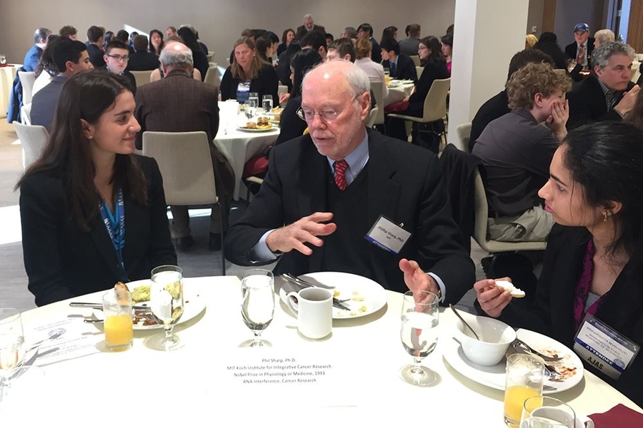 AJAS attendees Jessica Frank (left) and Sriharshita Musunuri (right) chat with MIT Professor Phillip Sharp, former AAAS president and Nobel laureate.