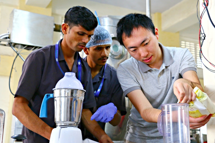 MIT graduate student Tonghan Gu (right) works with technicians at a facility in Vasai, India, to produce a batch of ready-to-use therapeutic food in powdered form. The formula he has developed uses local ingredients to make it more appealing to children.