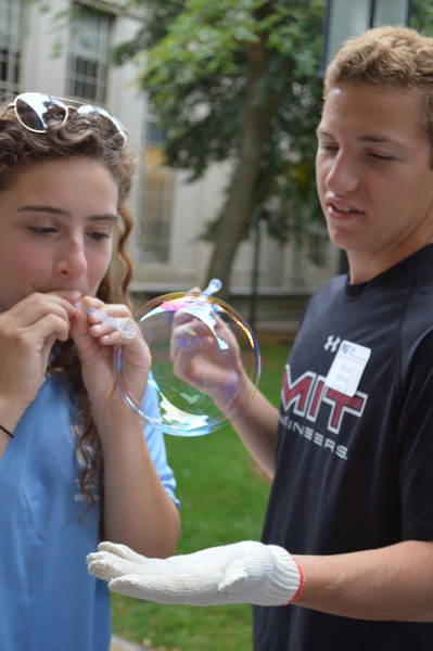 Camp attendees of all ages experimented mixing different solutions for soap bubbles and observing how bubbles bounce as part of an activity on fluid mechanics.