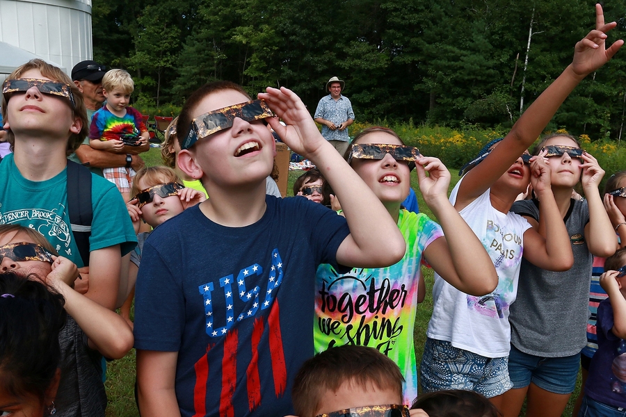 Families at MIT Wallace Astrophysical Observatory practice safe solar viewing with eclipse glasses.