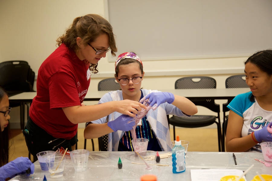 WIC member Carly Schissel helps one girl to make her borax slime at the Chemistry in Materials Experiment Station.
