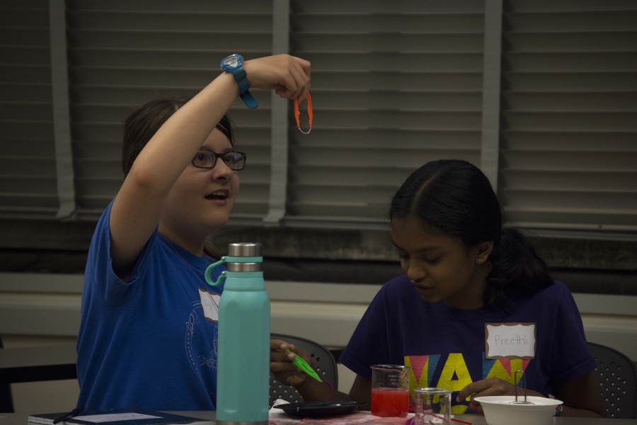 A young scientist examines a clump of DNA extracted from her strawberry mixture.