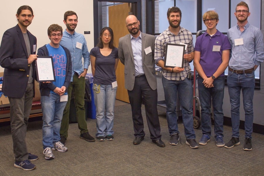 At center is Mike Tarkanian, a senior lecturer in the Department of Materials Science and Engineering and MADMEC competition organizer. Flanking him are two teams, Geoworks (left) and DUMBLEDORE (right), which split second and third place prizes of $7,000 and $5,000.