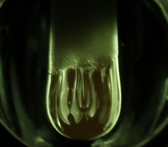 A molten hanging droplet, or pendant (at center), forms from an aluminum oxide rod under intense heat and light from xenon lamps. Using this process, MIT researchers have demonstrated a new electrochemical method to study thermodynamic processes in a molten oxide melt at temperatures above 2,000 degrees Celsius. 